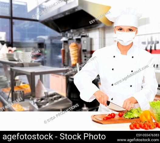 female chef in mask cutting vegetables at kitchen