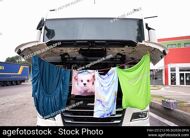 15 October 2023, Italy, Bologna: A truck driver dries his laundry on the open hood of a truck at a rest stop. Photo: Sebastian Kahnert/dpa