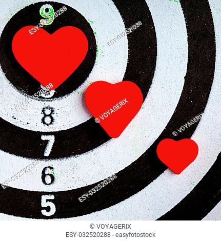 Closeup of old black and white target with red hearts symbols bullseye as love background. Valentines day