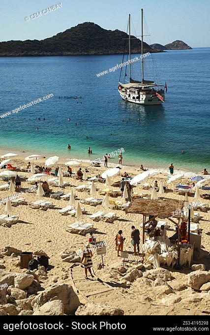 People swimming and sunbathing at the sandy beach of Kaputas with a cruise ship at the background, Kas, Antalya Province, Mediterranean Coast