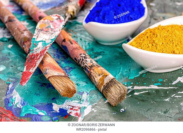 Brush, spatula and color pigments on a wooden palette
