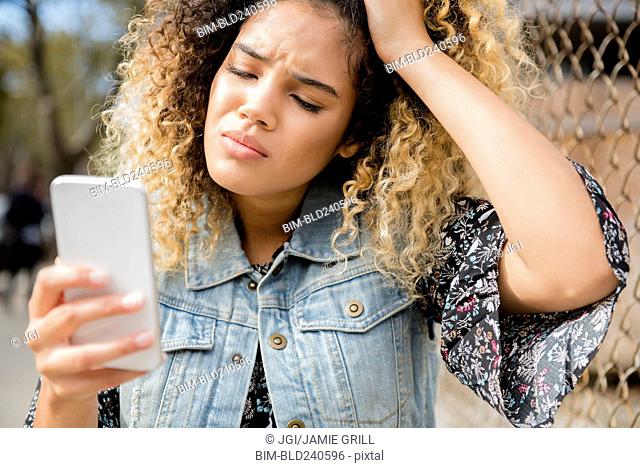 Unhappy Mixed Race woman texting on cell phone