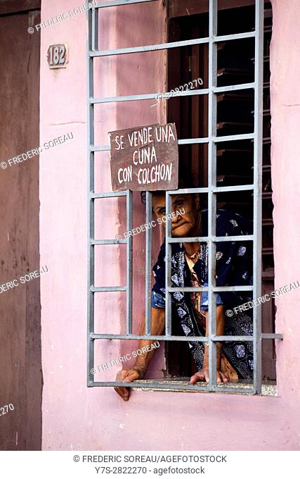 Man looking street in barred window, Trinidad, Cuba