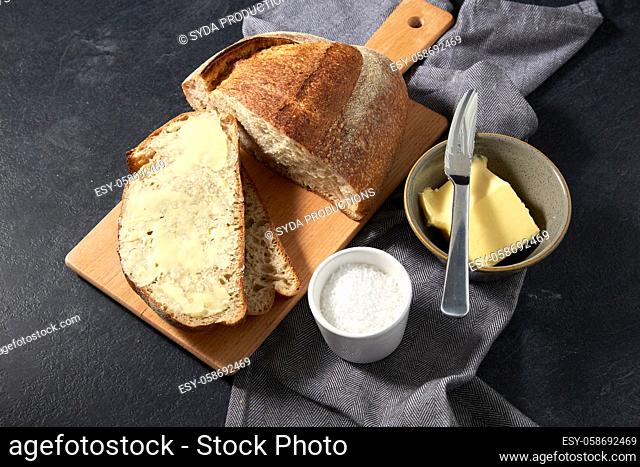 close up of bread, butter, knife and salt on towel