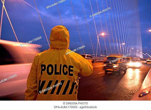 Traffic cop in raincoat guiding traffic on bandra worli rajiv gandhi sea link , Bombay Mumbai , Maharashtra , India