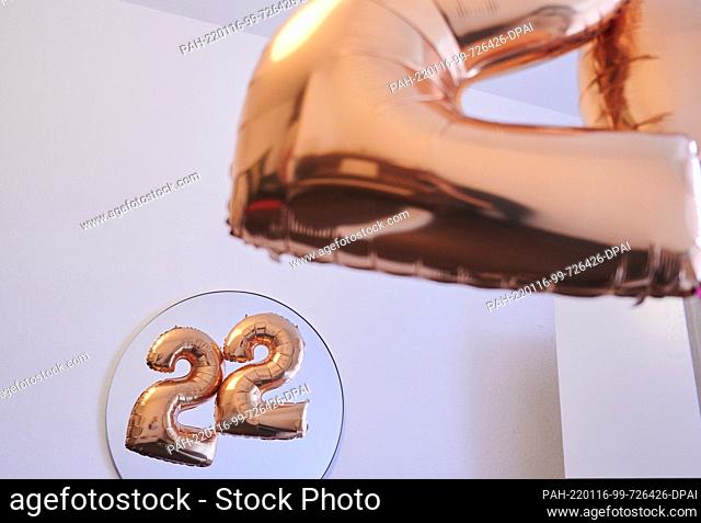 PRODUCTION - 13 January 2022, Berlin: ILLUSTRATION - Two golden balloons in the shape of the number 2 are reflected in a mirror