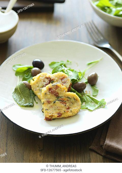 Heart-shaped semolina fritters on herb salad with olives