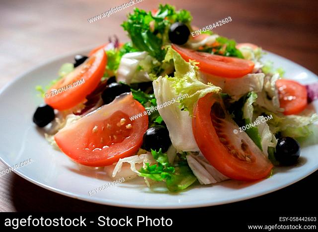 Healthy food concept. Vegetable salad with green lettuce, red tomatoes and black olives. Colorful natural vitamin appetizer