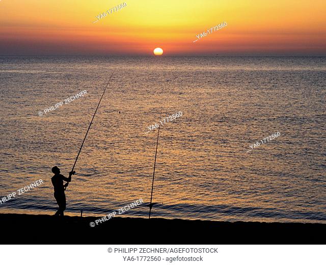 Man fishing in the sunset at Capo d'orlando, Siciliy