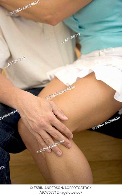 Close-up of mans hand on attractive female legs