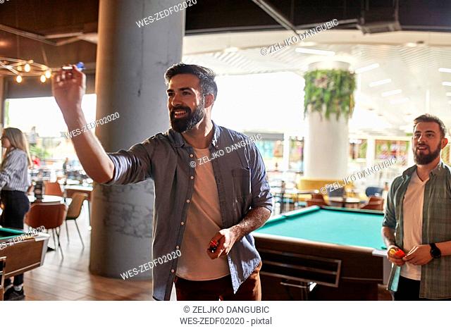 Smiling man playing darts