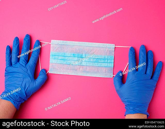 hands holds a medical mask against viruses and bacteria on a pink background, protective medical tool, top view
