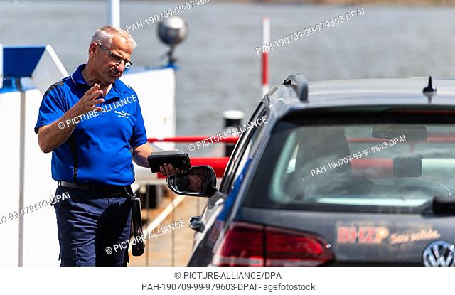 01 July 2019, Lower Saxony, Darchau: Ferryman Marian Klärner collects money on the Elbe ferry ""Tanja"". It's only a few hundred meters
