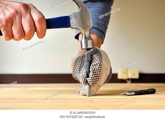 Wooden floor renovation, punching nails with hammer and puncher to prepare floors for sanding