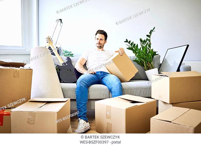 Frustrated man sitting on couch surrounded by cardboard boxes