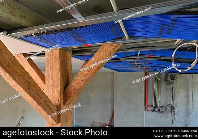 PRODUCTION - 22 June 2023, Brandenburg, Petersdorf: On a construction site in one room of a house, capillary tube mats are installed on the ceiling as surface...