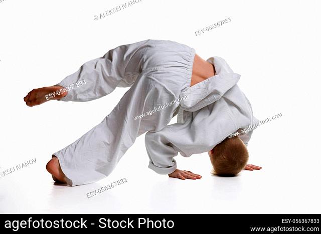 Judo boy doing warm-up spinning around himself while standing on his head