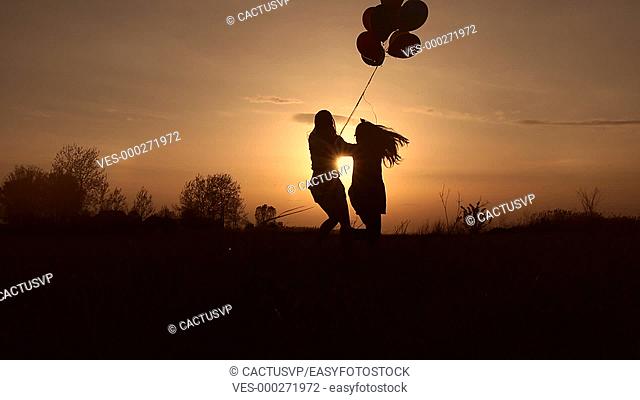 Mother and daughter playing in field at sunset