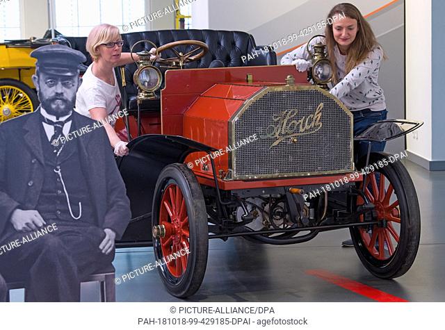 18 October 2018, Saxony, Zwickau: Two employees of the August Horch Museum in Zwickau push a Horch ""Model 2"" with 12 HP into position next to a portrait of...