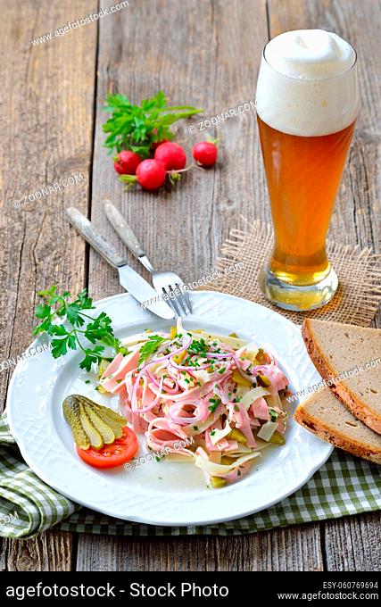 Deftiger Schweizer Wurstsalat mit Käsestreifen und Essiggurken dazu rustikales Bauernbrot sowie ein Weizenbier ? Hearty sausage salad with cheese strips
