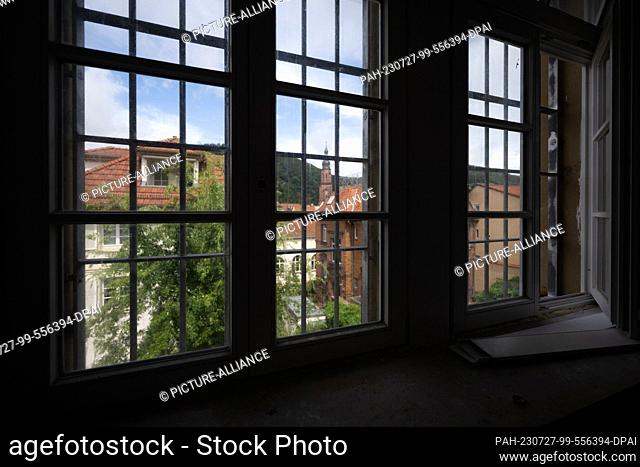 25 July 2023, Baden-Württemberg, Stuttgart: Roofs of Heidelberg's old town can be seen through a barred window of the ex-prison ""Fauler Pelt""
