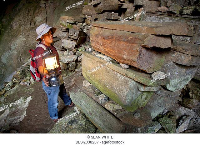 A Tour Guide Uses A Lantern To Look At The Many Coffins In The Entrance To Lumiang Burial Cave Near Sagada, Luzon Philippines