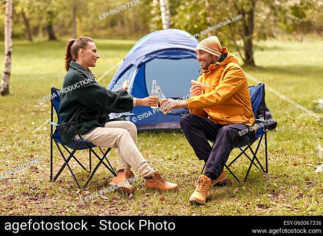 couple drinking beer with sandwiches at tent camp