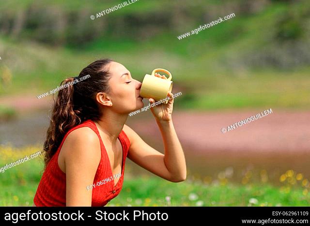 Side view portrait of a woman drinking coffee from mug in the mountain
