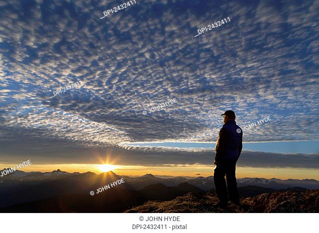 View of Coast Mountains and hiker at sunrise in the alpine on Douglas Island in Alaska's Tongass National Forest, Juneau. Alaska