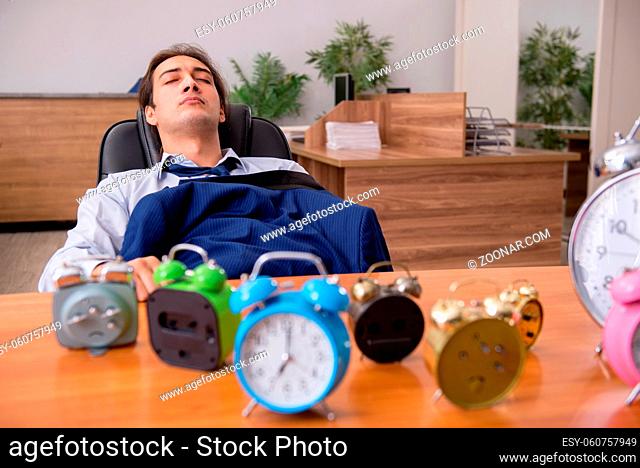 Young businessman sleeping in the office in time management concept
