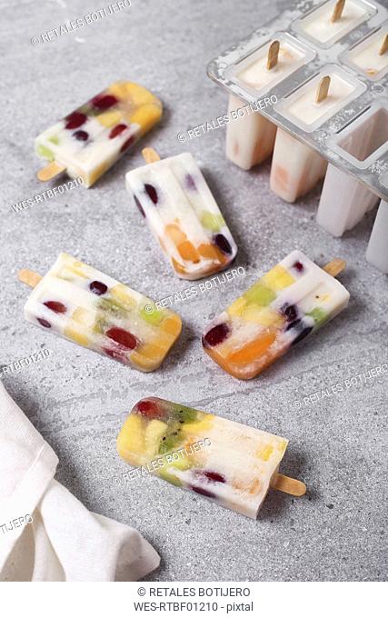 Homemade fruits and yogurt ice lollies on marble