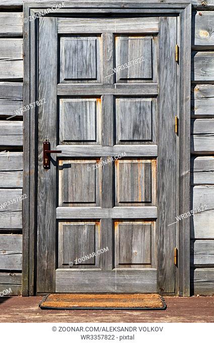 The door in the old rural house is made of the non painted grown weathered old pine and fir-tree boards