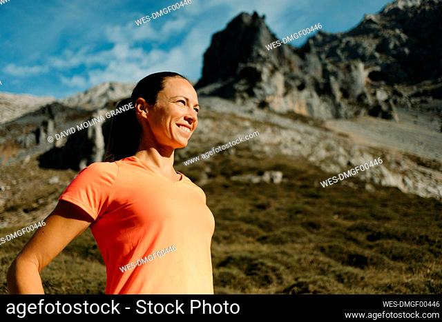Female explorer smiling while standing against mountain at Cares Trail in Picos De Europe National Park, Asturias, Spain