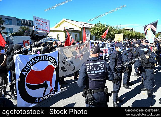 04 October 2020, Baden-Wuerttemberg, Konstanz: Counter-demonstrators hold a banner with the inscription ""Antifascist Action"" while police officers prevent...