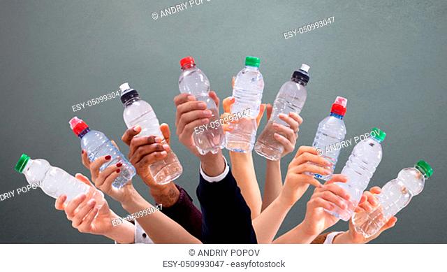 Group Of Different People Holding Water Bottles In A Row Against Green Background