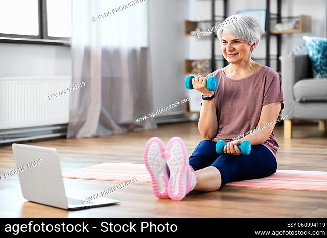 woman with laptop and dumbbells exercising at home