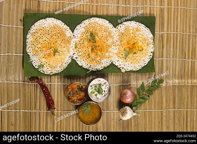 Thick spongy dosas served together with coconut chutney and sambhar on banana leaf