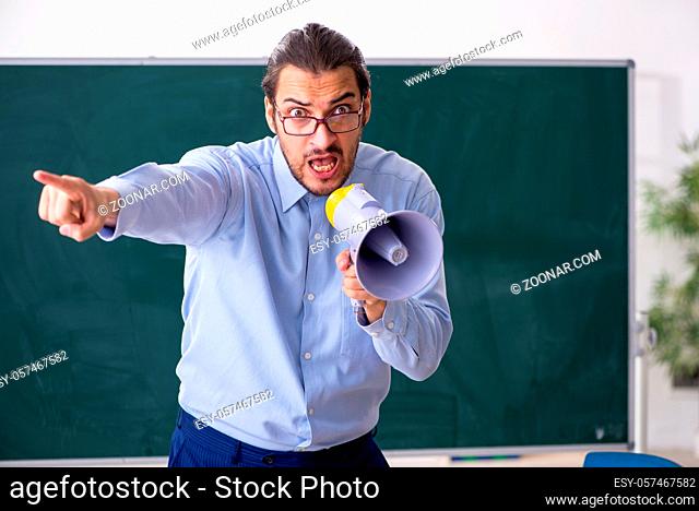 Young teacher in the classroom holding megaphone