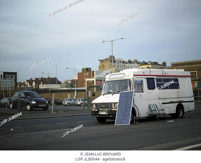 England, East Sussex, Hove, An old ambulance parked on the roadside with a solar panel and chair in Hove