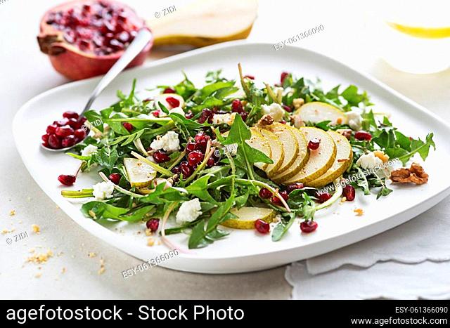 Healthy dandelion salad with pear fruit, pomegranate and fresh cheese close up