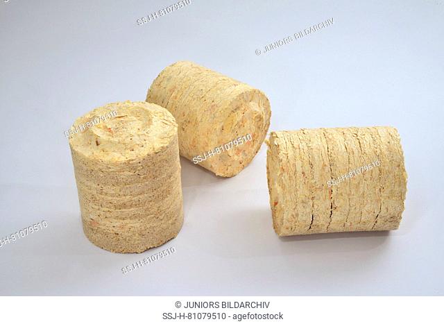 Three thick wood pellets, as used in large combustion plants. Studio picture against a white background