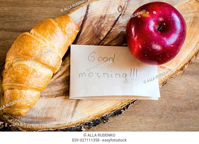 Apple, Croissant and Good Morning Note on Rustic Wooden Background. Selective Focus. Concept Breakfast