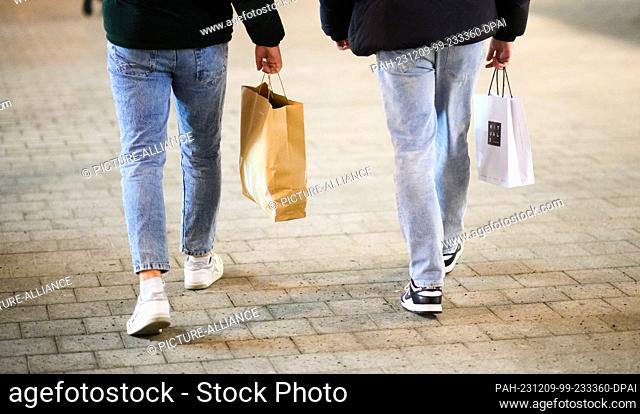 07 December 2023, Lower Saxony, Hanover: Two passers-by walk through the city center with shopping bags. Retailers in Lower Saxony can look back on a weak year...