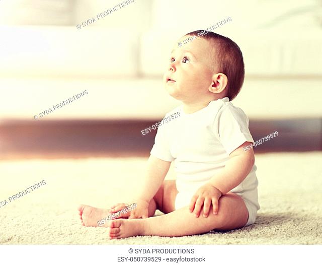 happy baby boy or girl sitting on floor at home