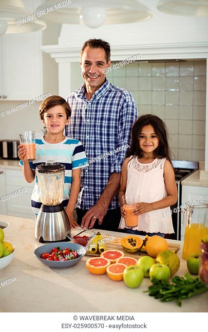 Portrait of father and kids holding glass of smoothie