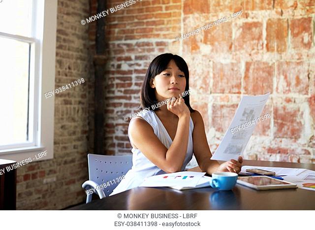 Businesswoman Making Notes On Document In Boardroom