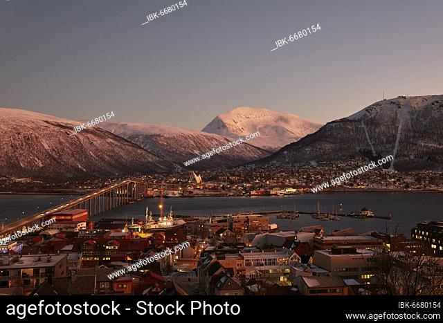 View of the harbour and the city with Tromsø Bridge and Ice Sea Cathedral, behind Tromsdaltinden and Storsteinen, twilight in the polar night, Tromsø, Troms