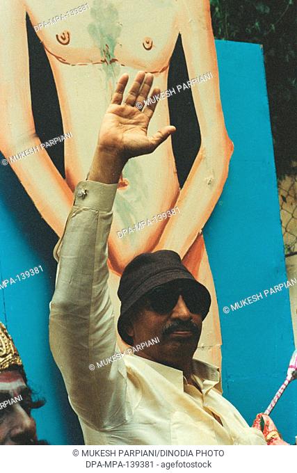 Man standing near nude cut-out , poster of bollywood actor Amitabh Bachchan
