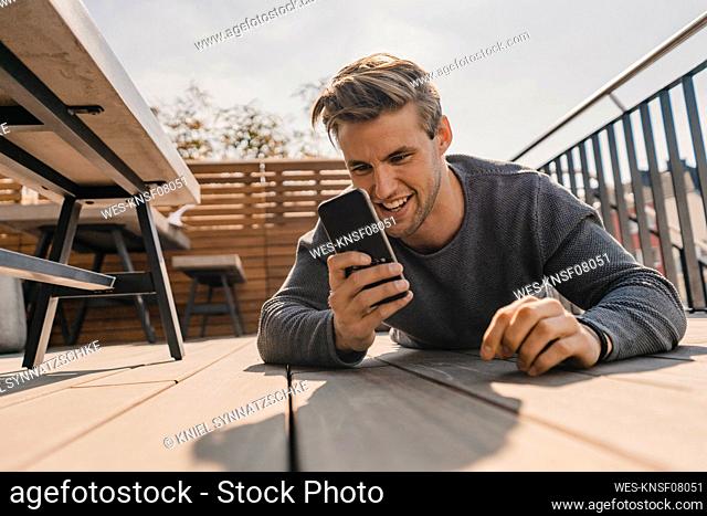 Young man using smartphone on the bacony