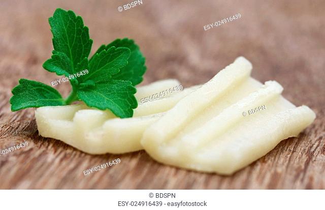 Chewing gum with green stevia on wooden surface
